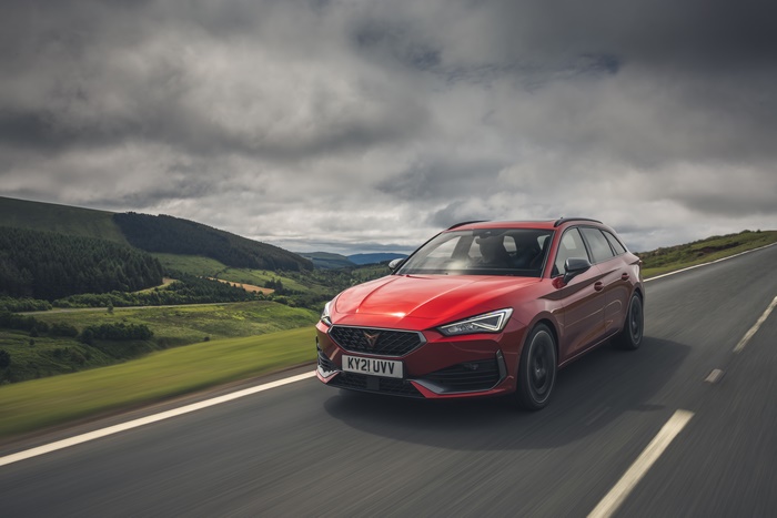 Red 2021 Cupra Leon Estate driving on a scenic road