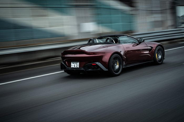 Red Aston Martin Vantage Roadster driving on highway