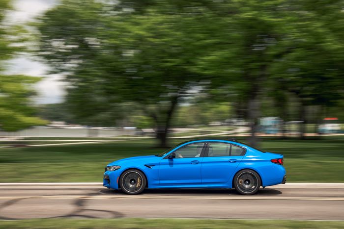 Blue 2021 BMW M5 Competition driving on road