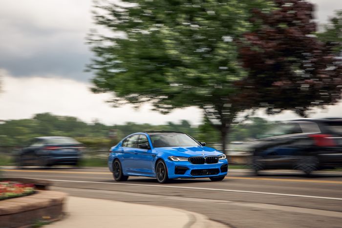 Blue 2021 BMW M5 Competition driving on road