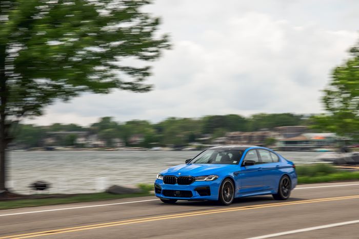 Blue 2021 BMW M5 Competition driving by a lake