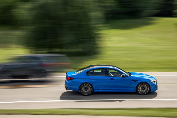 Blue 2021 BMW M5 Competition driving on road