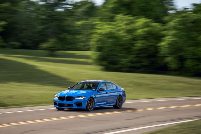 Blue 2021 BMW M5 Competition driving on a road