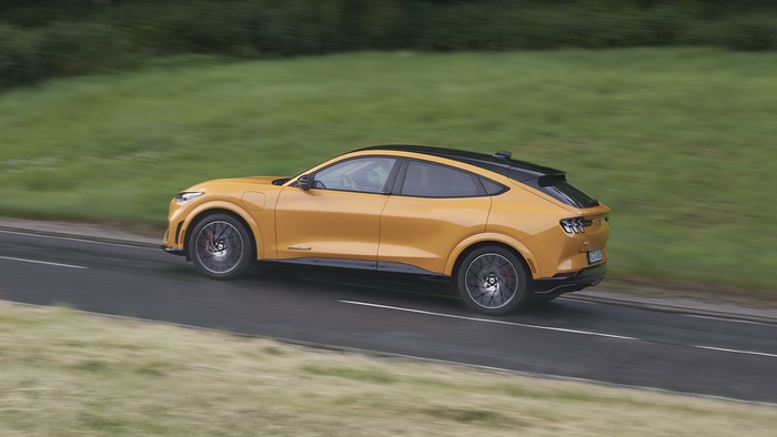 Orange Ford Mustang Mach-E GT driving on a road