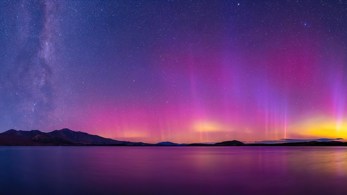 Aurora Borealis over a lake and mountains at night