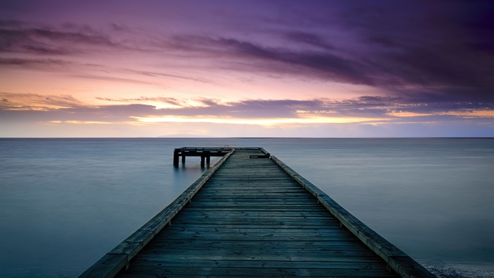 Wooden pier extending into the sea at sunset