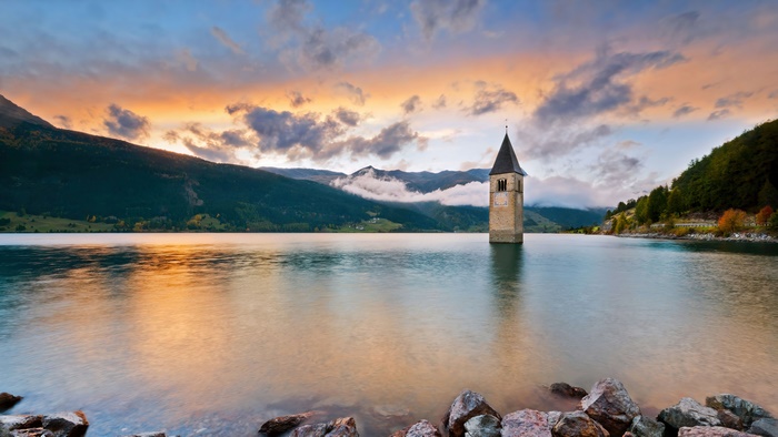 Submerged church tower in a lake at sunset, Italy