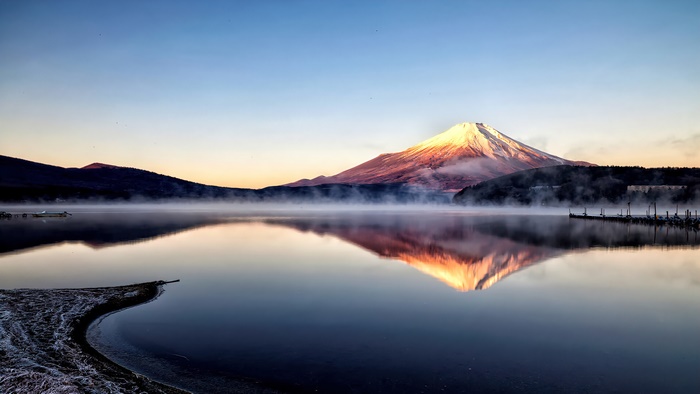 Mount Fuji reflected in a misty lake at sunrise