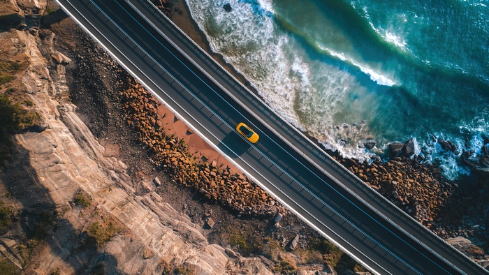 Yellow car on a coastal road, aerial view