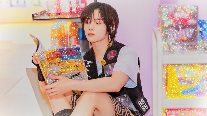 Beomgyu from TXT holding a sparkly book