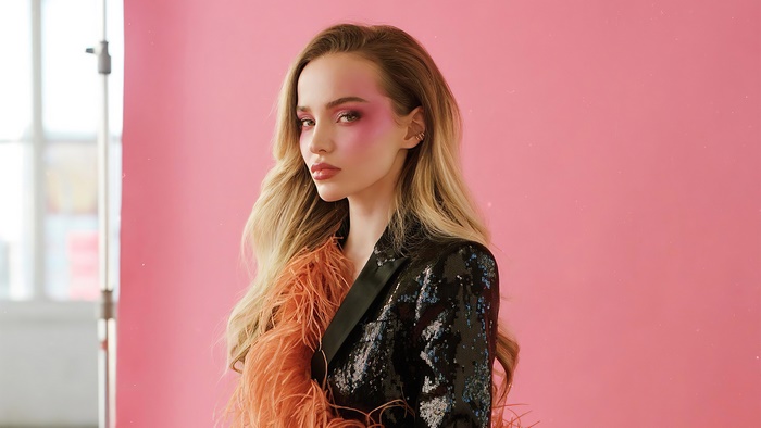 Dove Cameron in a sequined jacket with orange feathers