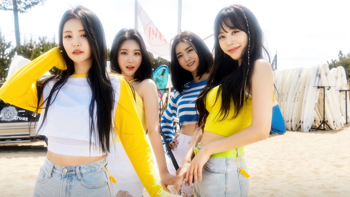 Brave Girls members on a beach with surfboards