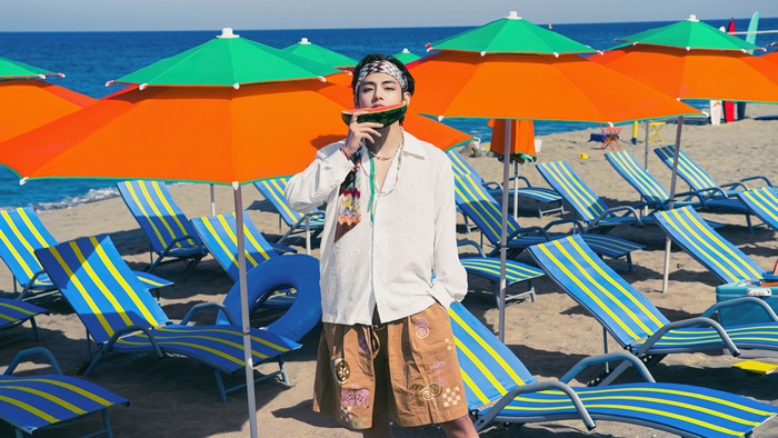 V from BTS eating watermelon on a beach
