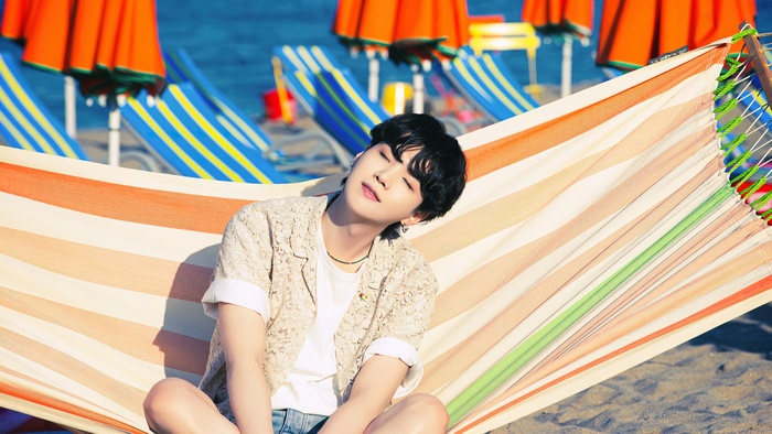 Suga from BTS relaxing on a beach hammock