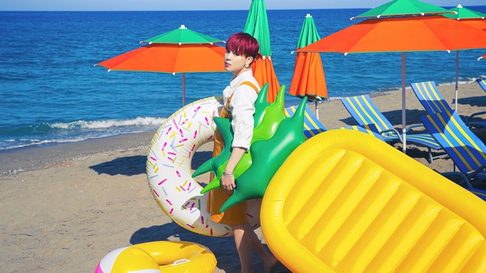 Jimin from BTS holding inflatable toys on a beach