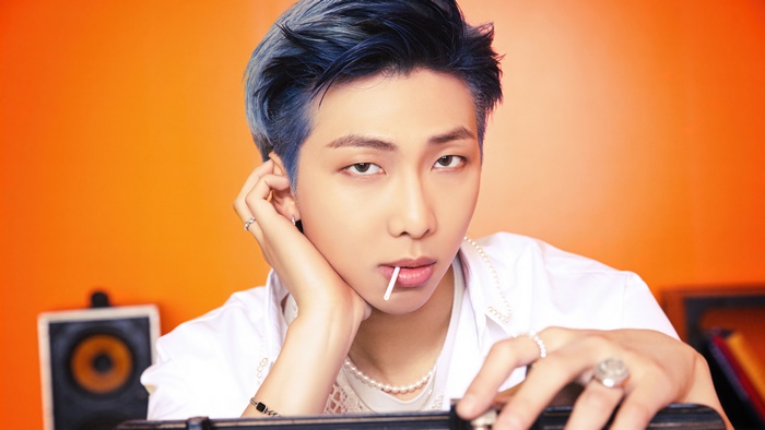 RM from BTS with blue hair holding a lollipop