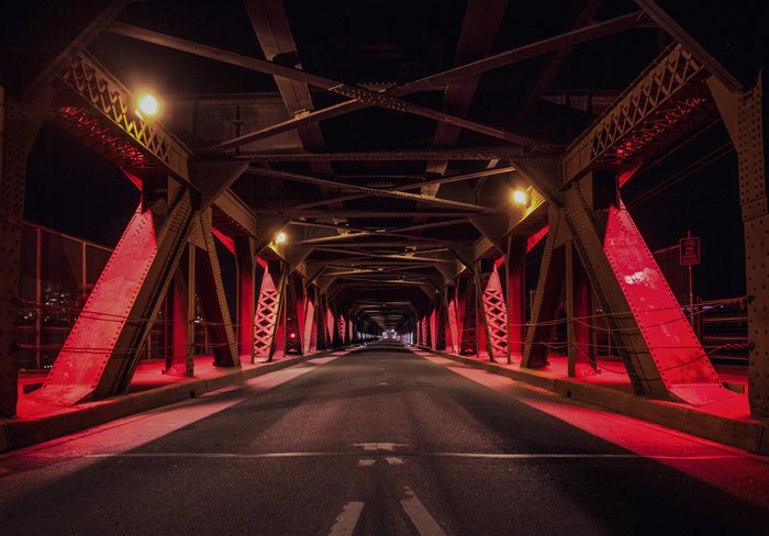 Red illuminated bridge at night with road