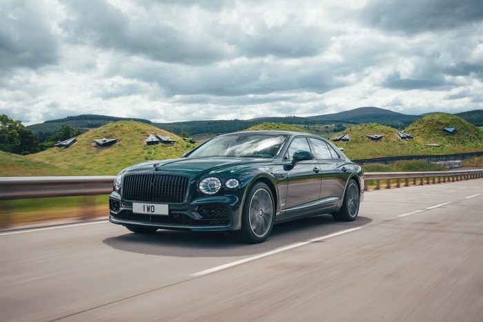 Green Bentley Flying Spur Hybrid driving on a road