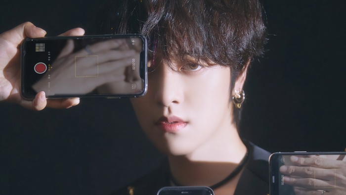 Ravn from ONEUS holding phones in front of face