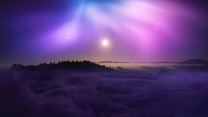 Mountain range above clouds with aurora borealis and stars