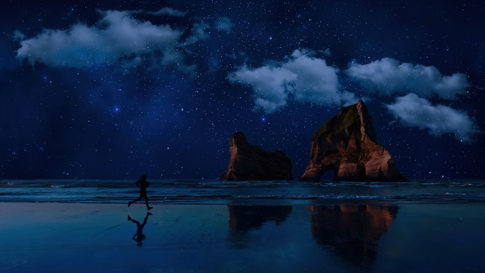 Man jogging on beach at night under starry sky