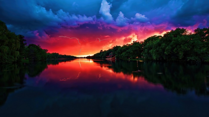 Thunderstorm over a river at sunset with lightning