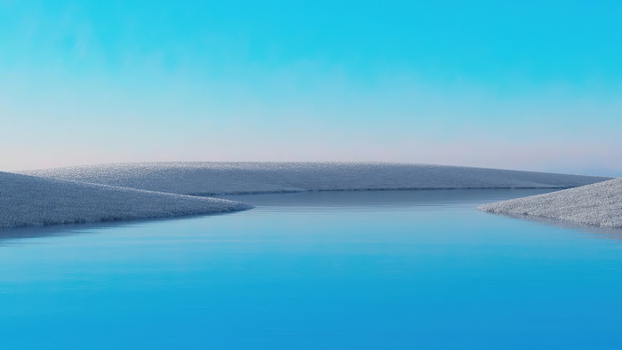 Calm blue water surrounded by snow-covered hills under a clear sky