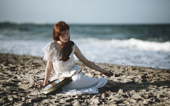 Redhead woman in white dress on beach with mirror