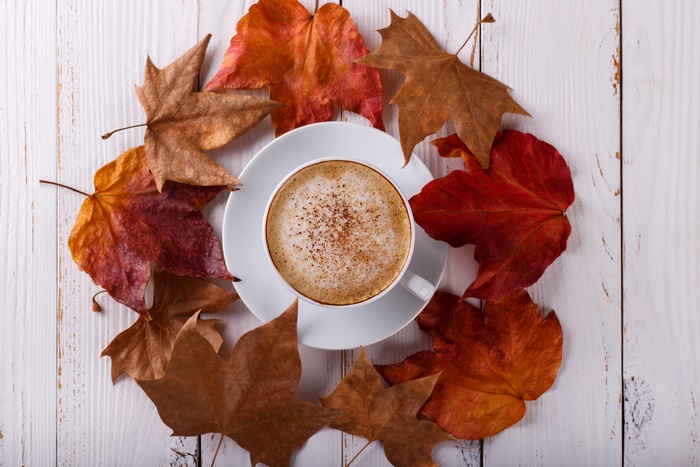 Coffee cup surrounded by autumn leaves