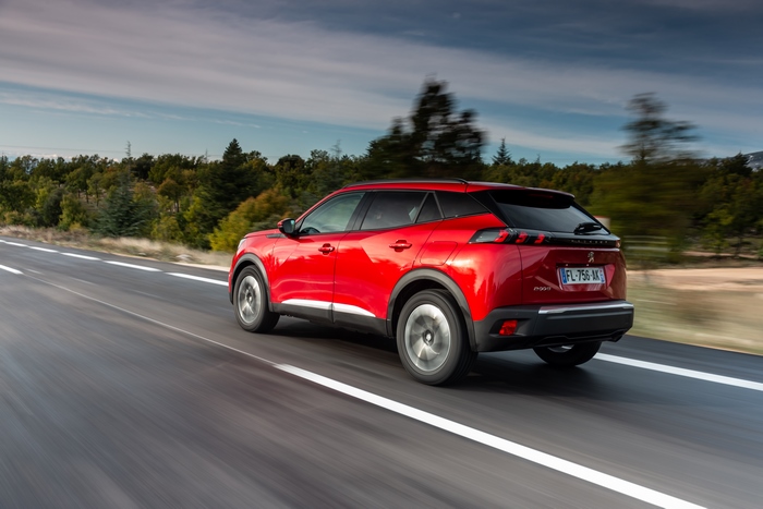 Red Peugeot 2008 SUV driving on a road