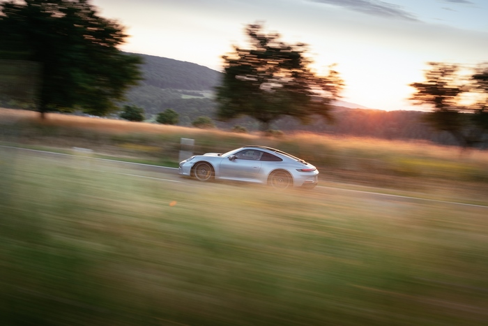 Silver Porsche 911 GT3 Touring on a country road at sunset