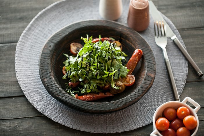 Salad with tomatoes and sausage on a wooden table