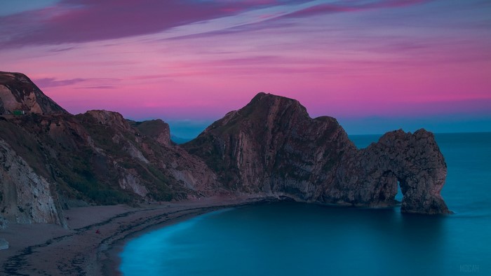 Durdle Door rock formation on a beach at sunset