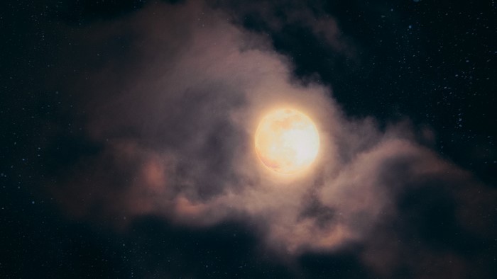 Moon behind clouds in a starry night sky