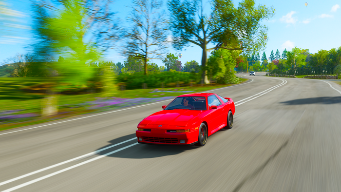 Red Toyota Supra driving on a road in Forza Horizon 4
