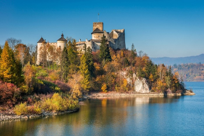Niedzica Castle on a hill overlooking a lake in Poland during fall