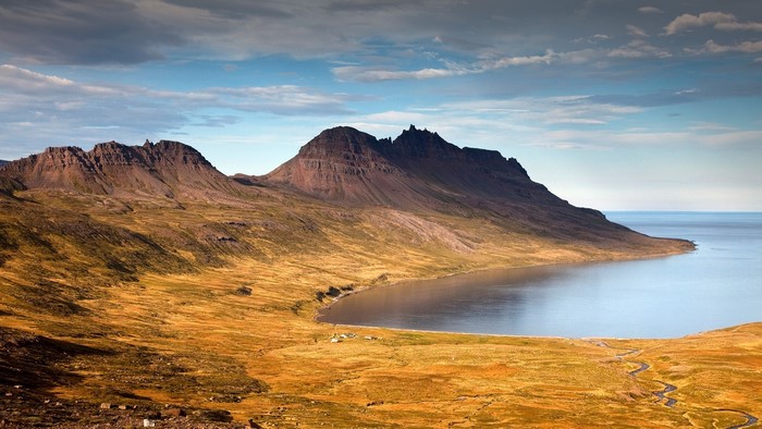 Mountainous fjord landscape with calm sea and cloudy sky
