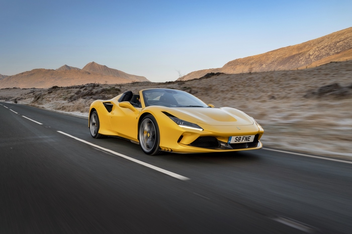 Yellow Ferrari F8 Spider driving on a road