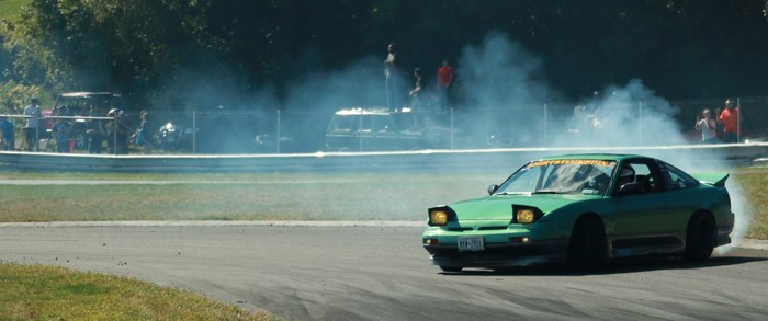 Green drift car on a race track with smoke
