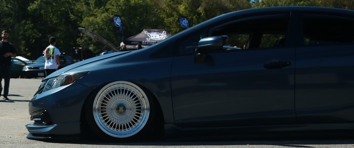 Dark blue car with custom wheels at an outdoor event