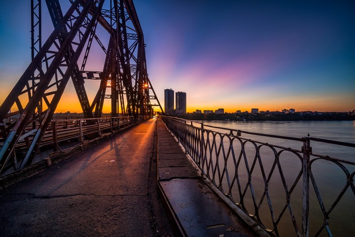 Long Bien Bridge at sunset over a river