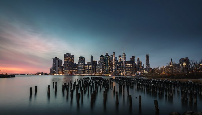 New York City skyline at dusk with wooden pilings in the foreground