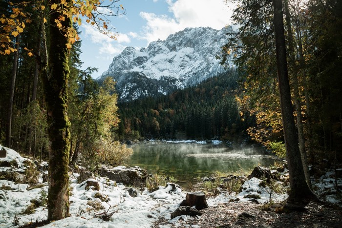 Snowy mountains and forest by a misty lake