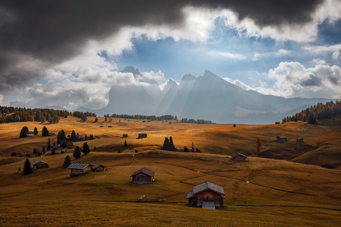 Mountain landscape with cabins and dramatic clouds