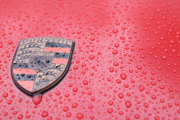 Porsche logo with water drops on red surface