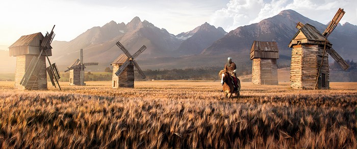 Knight on horseback in a field of windmills with mountains