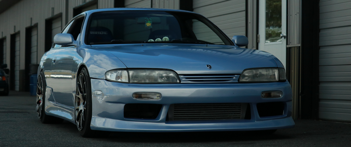 Blue Nissan Silvia S14 parked outside garage