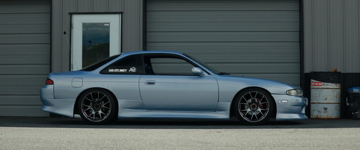 Silver Nissan S14 parked outside a garage
