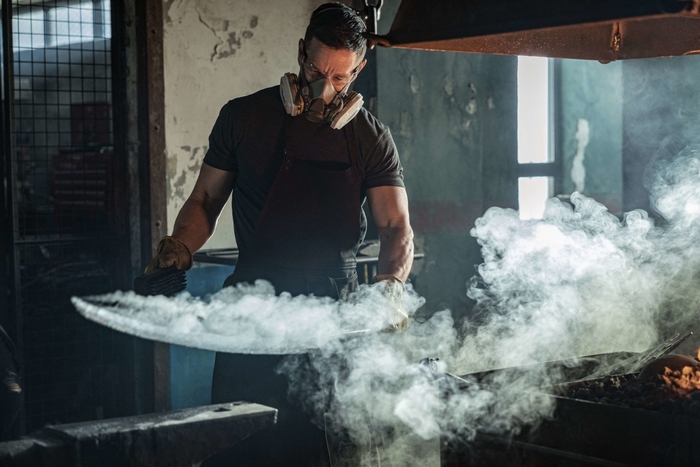 Blacksmith working with a sword and smoke