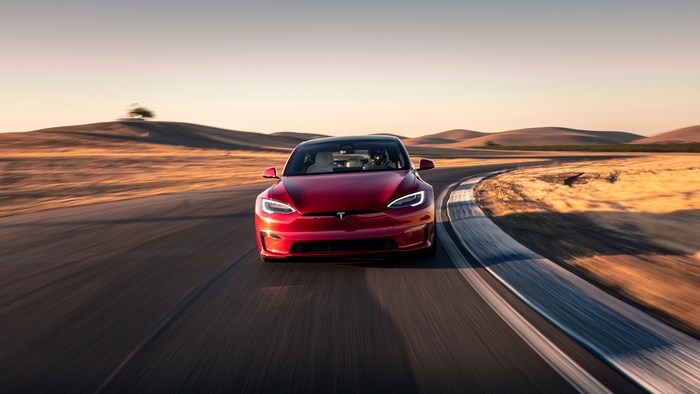 Red 2021 Tesla Model S Plaid driving on a road